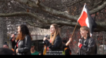 Ngā Hinepūkōrero video still from BLM rally NZ June 2020. Three people on stage doing spoken word into microphones. Tinorangatiratanga flag in the background.